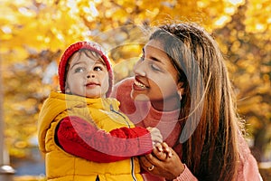 a happy African-American mother with her baby in an autumn park with yellow leaves