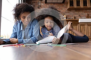 Happy African American mother with little daughter drawing together
