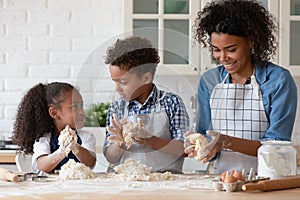 Happy African American mother with little kids kneading dough