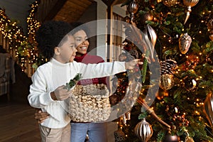 Happy African American mother and little son decorating Christmas tree
