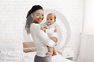 Happy African American Mother Posing With Baby Toddler In Bedroom