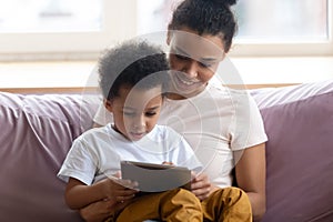 Happy african american mother sitting with son on couch.