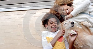 Happy african american mother and son lying on floor, with their pet dog, copy space, slow motion