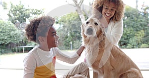 Happy african american mother and son sitting on floor, petting dog, slow motion