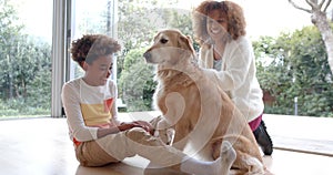 Happy african american mother and son sitting on floor, petting dog, slow motion