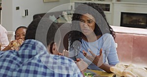 Happy african american mother talking and eating lunch with family at home