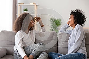 Happy African American mother and teen daughter chatting at home