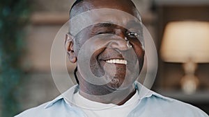 Happy african american optimistic senior friendly gentleman carefree ethnic adult man wink dark eyes flirting. Close up