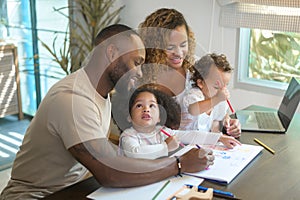 Happy African American parent playing and drawing with daughters in home
