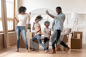 Happy african american parents and children dancing celebrating moving day