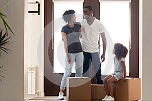 Happy African American parents standing in new house with daughter