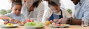 Happy African American parents teaching sibling kids to cook