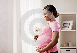 Happy african american pregnant woman with flower