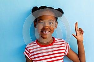 Happy african american schoolgirl doing sign language with hand over blue background