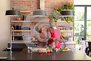 Happy african american senior couple cooking together in kitchen