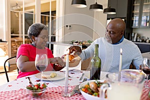 Happy african american senior couple having christmas meal at home
