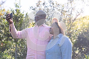 Happy african american senior couple taking selfie outdoors