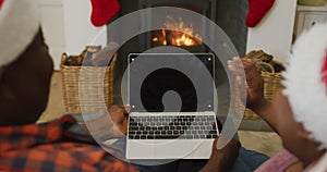 Happy african american senior couple using laptop with copy space and sitting on the floor