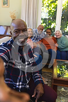 Happy african american senior man doing selfie and smiling in sunny living room, copy space