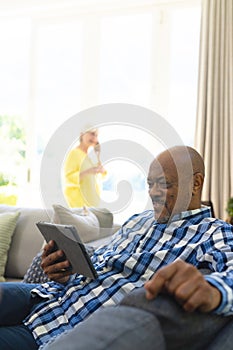 Happy african american senior man having video call in sunny living room, copy space