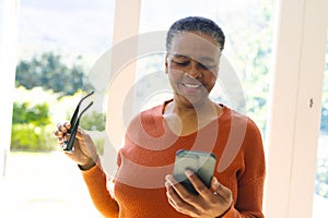 Happy african american senior woman with glasses, having video call in sunny living room, copy space