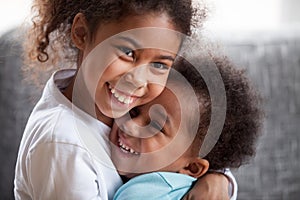 Happy African American siblings embracing, sitting together