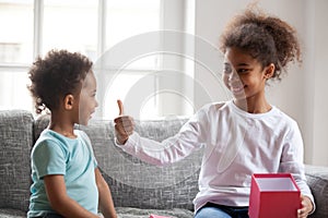 Happy African American siblings sitting together on couch