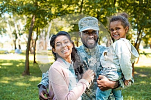 happy african american soldier in military uniform looking at camera with family