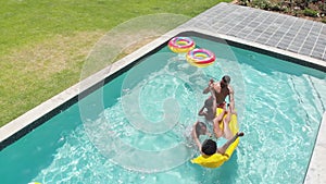 Happy african american son and daughter jumping into swimming pool to parents