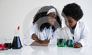 Happy african american student girl and boy is learning and test science chemical with colorful liquid in tube test and beaker in