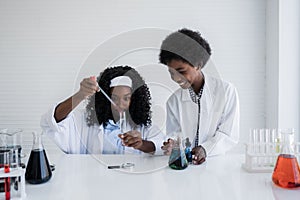 Happy african american student girl and boy is learning and test science chemical with colorful liquid in tube test and beaker in