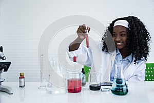 Happy african american student girl is learning and test science chemical with colorful liquid in tube test and beaker in