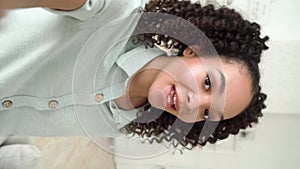 Happy African American teen girl holding phone talking to mobile camera.