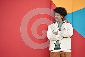 Happy African American teen guy looking away at colorful wall background.