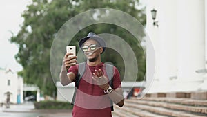 Happy african american tourist man having online video chat using his smartphone camera while travelling in Europe