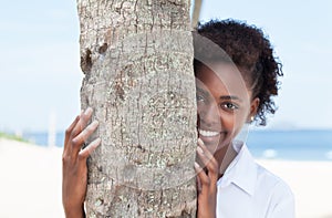 Happy african american woman behind a tree