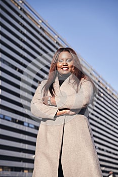 Happy African American woman business leader CEO chief executive standing in front of company building