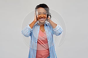 Happy african american woman closing ears by hands