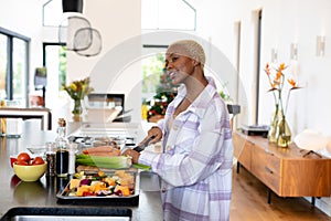 Happy african american woman cooking in kitchen, chopping vegetables