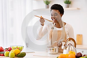 Happy African American Woman Cooking Tasting Dinner In Kitchen Indoor