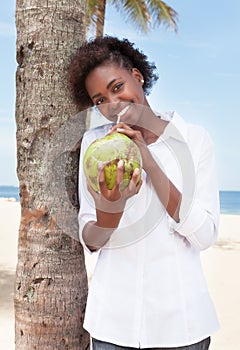 Happy african american woman drinking coconut water