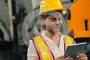 Happy African American Woman Engineer Worker Supervisor looking at Tablet computer to control operate maching in Heavy Industry