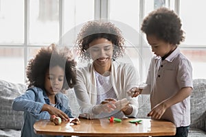 Happy African American woman with and kids playing with plasticine