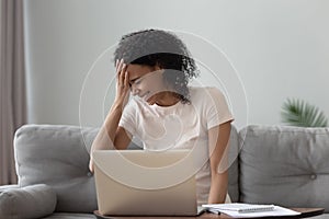 Happy African American woman laughing at funny joke, using laptop