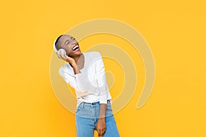 Happy African American woman laughing while listening to music on wireless headphone