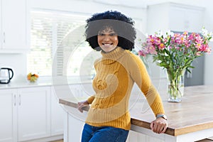 Happy african american woman leaning at kitchen counter at home, copy space
