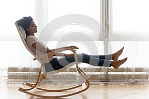 Happy African American woman relaxing in comfortable chair at home