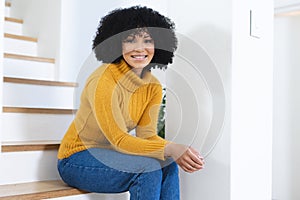 Happy african american woman sitting on stairs at home, copy space