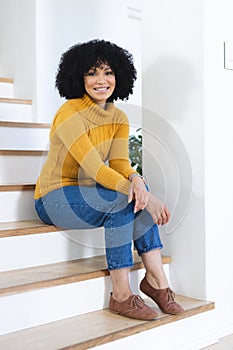 Happy african american woman sitting on stairs at home, copy space