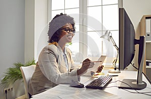 Happy African American woman smiling while working with laptop